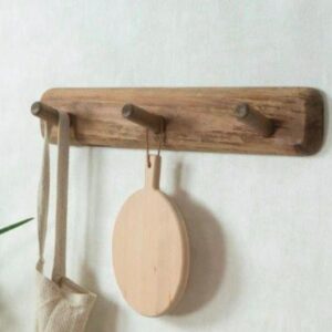 Rustic farmhouse wooden wall peg rack with tote bag and round cutting board in minimalist kitchen.