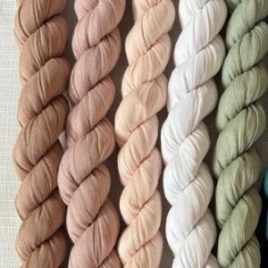 Braided skeins of neutral cotton fabric yarn in nude, blush, white, and sage green—craft crochet knitting flatlay