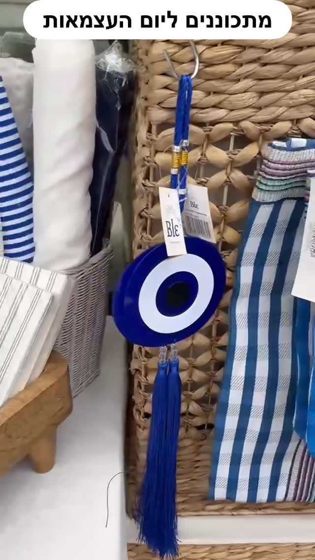 Blue-and-white home decor with evil eye nazar tassel on wicker basket, striped towels; Israel Independence Day theme.