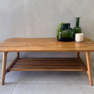 Mid-century wood coffee table with slatted shelf, styled with green glass vases on concrete tile floor, living room decor.