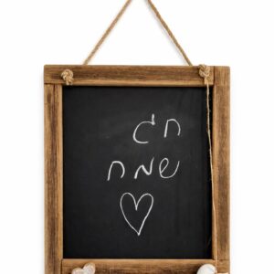 Rustic wooden chalkboard sign with Hebrew 'Chag Sameach' and heart doodle, hanging by rope with small heart accents