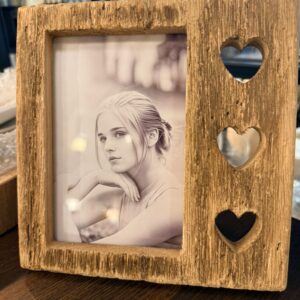 Rustic wood picture frame with heart cutouts displaying black-and-white portrait, farmhouse home decor on table