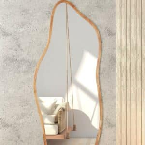 Organic wavy full-length mirror with wood frame reflecting rattan sofa and indoor swing in neutral boho living room.