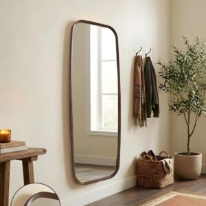 Modern entryway with full-length wall mirror, dark wood frame, coat hooks, woven basket, olive tree, neutral decor.