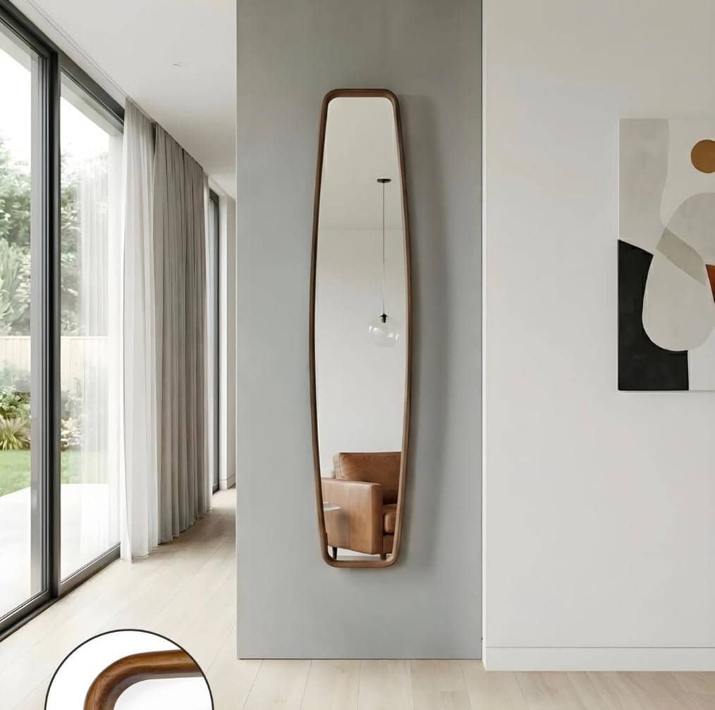 מראה צרה Modern full-length wall mirror with curved wooden frame in minimalist living room, reflecting tan armchair and pendant light