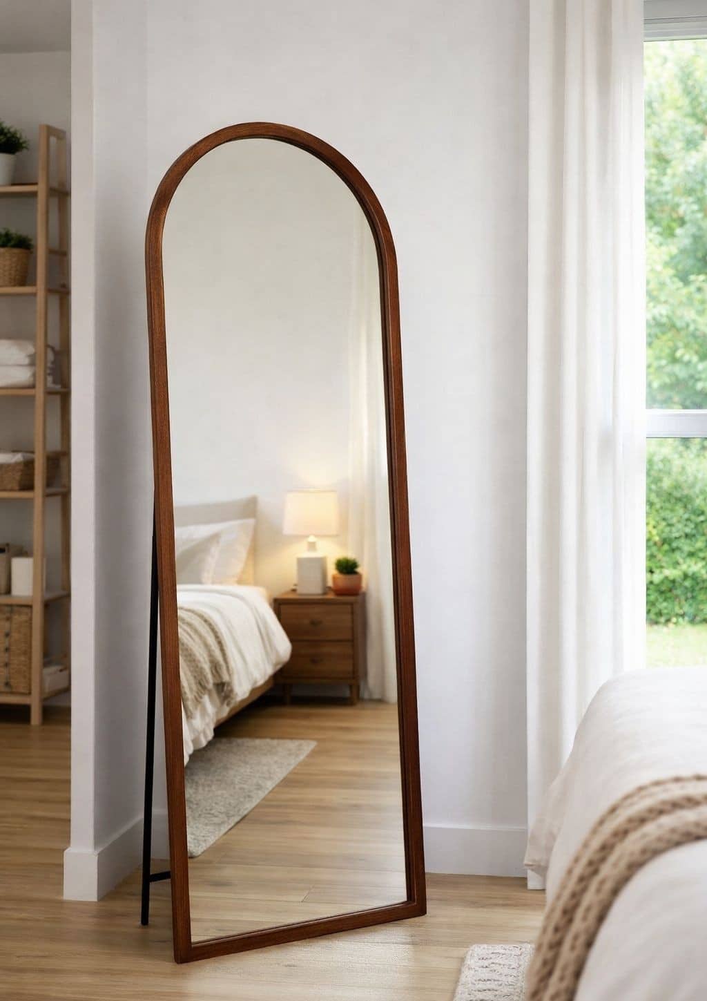 מראת קשת מסגרת עץ Arched full-length floor mirror with wooden frame leaning in a minimalist bedroom with neutral decor and natural light