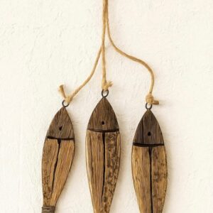 Rustic wooden fish wall hanging with three carved fish on jute rope, coastal farmhouse decor on white textured wall.