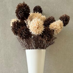 Brown and cream dried flowers in a tall white pedestal vase, minimalist decor on a gray concrete wall background