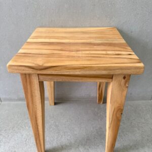 Minimalist solid wood stool with square top, natural finish and tapered legs on concrete floor