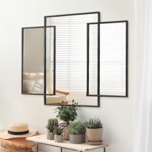 Modern black-framed triptych mirror above console with potted succulents; bright room with blinds and cozy chair reflection.