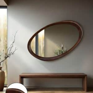 Modern entryway with large asymmetrical oval wood wall mirror above walnut bench, minimalist home decor.