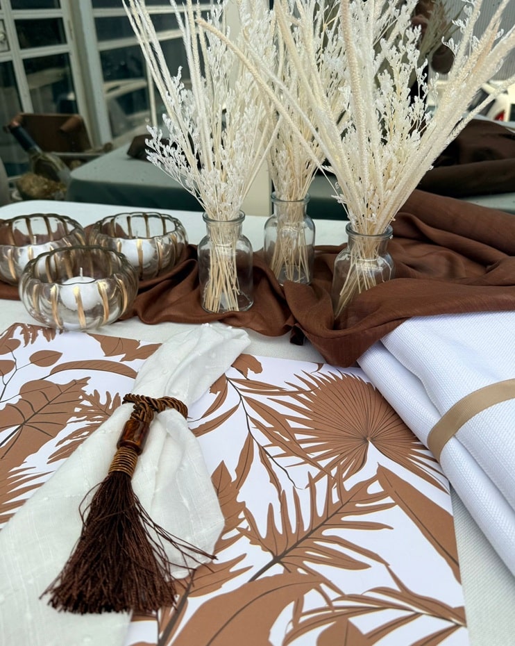 סט מואנה (3) Boho table decor with dried pampas in glass vases, brown runner, candles, and botanical placemats for rustic fall wedding.