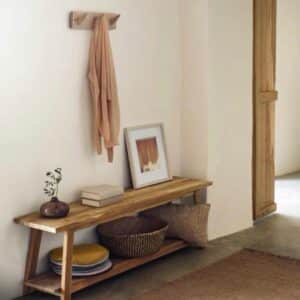 Modern rustic entryway with wood bench, coat rack, framed art, woven basket and pillows in neutral tones.